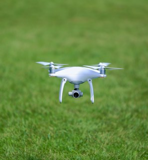 A drone flying over a lush green agricultural field.