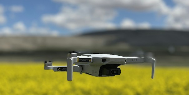 Close-up of a drone spraying crops in a sunny landscape.