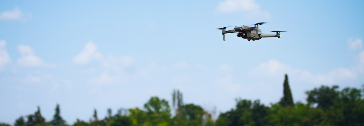 Aerial view of a drone flying over a green farm, capturing data.