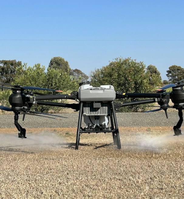 A close-up of a drone spraying crops in a farm.